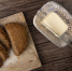 top view of woman hand cutting butter with knife and sliced sandwich bread on cutting board on wooden background - Газета Восход