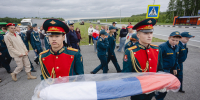 На фото — патриотическая акция на трассе: большая группа людей развернула длинный флаг России на разделительной полосе автомагистрали., Изображение. - Правительство Челябинской области