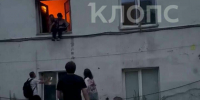 Александр удерживает женщину в окне, в ожидании людей, которые её поймают. Рядом на асфальте лежит второй пострадавший.  | Скриншот видеозаписи - Klops.Ru