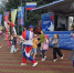 На мероприятии «Большая семья 2016» аниматоры в костюмах цветов российского флага танцуют в окружении детей и взрослых, на заднем плане — палатки, флаги «Челябинская область» и «Помогаем людям», а также грузовик «Развитие области»., Изображение. - Правительство Челябинской области