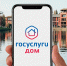 На фото — рука, держащая смартфон с открытым экраном приложения «Госуслуги Дом», на фоне современных жилых домов у водоёма - Коркинский муниципальный округ