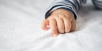 Newborn baby hand in white bed. Selective focus. - Краевое профобъединение