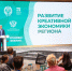 Министр экономического развития РФ Максим Решетников выступает на сцене на фоне зеленого баннера с надписью "Развитие креативной экономики региона", перед ним сидят слушатели за столом, Изображение. - Минэкономразвития