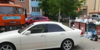 Белый автомобиль припаркован у переполненных мусорных контейнеров во дворе жилого дома. - Россошанский район