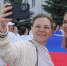 На фото две девушки делают селфи на фоне большого флага России. Автор фото – Елизавета Гриценко, пресс-служба Челябинского Регионального отделения Партии «Единая Россия», Изображение. - Правительство Челябинской области