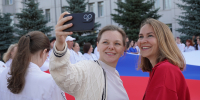 На фото две девушки делают селфи на фоне большого флага России. Автор фото – Елизавета Гриценко, пресс-служба Челябинского Регионального отделения Партии «Единая Россия», Изображение. - Правительство Челябинской области
