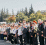 На фото — группа школьников и взрослых, выстроившихся в линию на улице: дети в парадной форме с цветами и медалями, рядом — учителя и другие взрослые, на фоне — городские здания и деревья. - Коркинский муниципальный округ