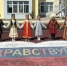 Дети в национальных костюмах стоят на школьном дворе, держась за руки перед нарисованным на асфальте сердцем с надписью «Здравствуйте». - Министерство образования и науки