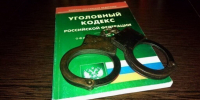 Металлические наручники лежат на книге «Уголовный кодекс Российской Федерации» на деревянном столе - 168.Ru