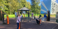 Дети и взрослые занимаются на уличных тренажёрах вокруг беседки во дворе жилого дома - 168.Ru