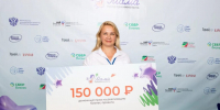 Женщина держит большой сертификат на денежный приз в 150 тысяч рублей на фоне стены с логотипами - 168.Ru