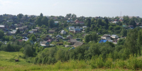 панорама сельской деревни с многочисленными деревянными домами и зелёными склонами - 168.Ru