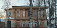 Двухэтажное старое деревянное здание с красными рамами окон, зима, берёзы и столб на переднем плане. - 168.Ru