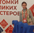 Улыбающаяся девушка в народном стиле на фоне баннера Всероссийского фестиваля «Потомки великих мастеров»: перед ней объёмные синие цифры «2026» на красной подставке, а на фоне — орнаменты и символ самовара. - Министерство образования и науки