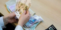 Человек пересчитывает российские банкноты за столом, рядом лежат пачки денег и калькулятор - 168.Ru