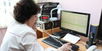 Медицинская работница в белом халате разговаривает по телефону и работает за компьютером. - 168.Ru