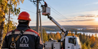 Электромонтеры проводят плановые работы на линии электропередачи в Ленинградской области, рядом с опорами воздушной линии находится специализированная техника, осенний лес на заднем плане. - SyasNews.Ru