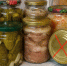 Несколько стеклянных банок с домашними консервами (солёные огурцы, овощи, мясной паштет, квашеная капуста); одна банка лежит на боку с красным крестом на крышке. - 168.Ru