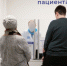 Пациенты у окошка регистратуры/службы помощника пациента в интерьере поликлиники; за стеклом виден медработник. - 168.Ru