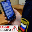 Человек в форме держит смартфон с сообщением от имени службы судебных приставов; внизу размещено предупреждение о мошенниках - 168.Ru