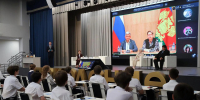 На фото — школьное профориентационное занятие «Россия — мои горизонты»: ученики в актовом зале смотрят трансляцию на большом экране, на сцене — организаторы мероприятия. - Министерство образования и науки