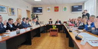 Участники заседания за длинными столами поднимают руки во время голосования, двое мужчин ведут съёмку - 168.Ru