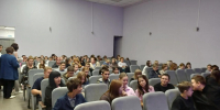 Зрители в небольшом зрительном зале: ряды серых кресел, в них сидят люди разных возрастов в актовом/культурно‑досуговом центре. - 168.Ru