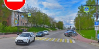 Улица с пешеходным переходом, припаркованными автомобилями и большим синим баннером «ВНИМАНИЕ! ОГРАНИЧЕНИЕ ДВИЖЕНИЯ!», сверху добавлен знак «въезд запрещён». - 168.Ru