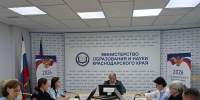 На фото — заседание в Министерстве образования и науки Краснодарского края: за длинным столом сидят участники в деловой одежде, перед ними таблички с именами, микрофоны и мониторы, на фоне — символика ведомства и баннеры с тематикой 2026 года. - Министерство образования и науки