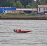 Красная гоночная моторная лодка с номером 23 плывёт по реке; на заднем плане берег с набережной/промышленными постройками и деревьями. - 168.Ru