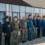 На фото группа сотрудников силовых структур и ведомств выстроилась в ряд перед современным зданием — рядом видны акустическая аппаратура и флагштоки, справа стоит женщина с микрофоном. - Коркинский муниципальный округ
