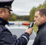 Сотрудник полиции проводит проверку водителя алкотестером у служебного автомобиля с проблесковыми лампами на просёлочной дороге - 168.Ru