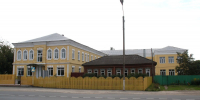 Старое жёлтое здание школы с полукруглыми окнами за жёлтым забором у дороги - Newsroom24.Ru
