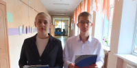Двое подростков идут по школьному коридору, держат папки/планшеты в руках - 168.Ru