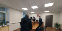 зал суда: судья за трибуной читает документ, двое мужчин стоят; на стене виден герб РФ и государственный флаг - 168.Ru