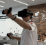 Юноша в VR‑шлеме с контроллерами демонстрирует работу с технологией виртуальной реальности в учебном классе, на фоне — другие учащиеся в форменной одежде и информационные стенды. - Министерство образования и науки