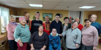Групповое фото участников и сотрудников в помещении дома ремёсел: люди разных возрастов, некоторые в народных костюмах, на фоне интерьера мастерской и плетёных изделий. - 168.Ru