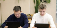 Двое молодых людей за партами работают на планшетах/ноутбуках в учебном классе/кабинете - 168.Ru