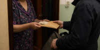 пожилая женщина в дверном проёме передаёт конверт с наличными курьеру - 168.Ru
