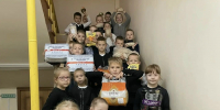 Группа школьников на лестнице держит большие пакеты корма и коробки с пожертвованиями для животных - 168.Ru