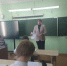 Взрослая женщина стоит у школьной доски и держит раздаточные листы; перед ней – несколько школьников за партами; в классе видны интерактивный экран и мелованная доска. - 168.Ru