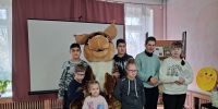 Группа детей и ростовая кукла (белочка) в детском отделе библиотеки на фоне проекционного экрана и книжной полки. - 168.Ru