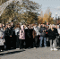 В городском парке им. И. Федько собралась большая группа людей, рядом с ними фотографы с камерами, а на фоне видна нарядная белая арка со звездой и осенние деревья. - Коркинский муниципальный округ