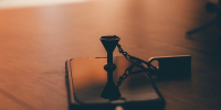 Песочные часы отражаются на тёмном экране смартфона, лежащего на столе - Newsroom24.Ru