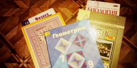 Стопка школьных учебников (Геометрия, Физика, Биология, Deutsch) на деревянном полу - 168.Ru