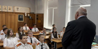 В классе сидят дети в форме, слушают преподавателя УМЦ. Помещение светлое, с окнами и портретами на стенах. - Министерство гражданской обороны и чрезвычайных ситуаций