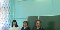 Ученики за партами в классе; у доски стоят три взрослые (одна в форме), школьная доска, учебники на столах. - 168.Ru