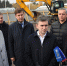 Несколько мужчин у строительной площадки: экскаватор JCB, временное ограждение стройплощадки и трибуны стадиона на заднем плане; микрофоны на переднем плане. - 168.Ru