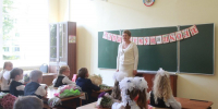 Учительница у школьной доски, первоклассники/ученики начальных классов за партами с букетами - 168.Ru