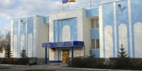 Бело-голубое здание суда с флагами над входом и молодыми елями у крыльца - Newsroom24.Ru